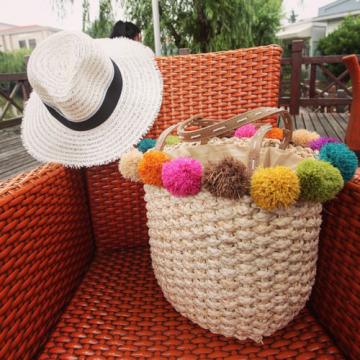 Women&#039;s handmade summer beach woven straw bag with colorful pom poms