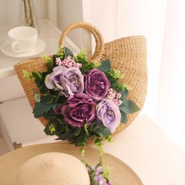 Women&#039;s handmade summer beach straw round bag with artificial flowers blossoms